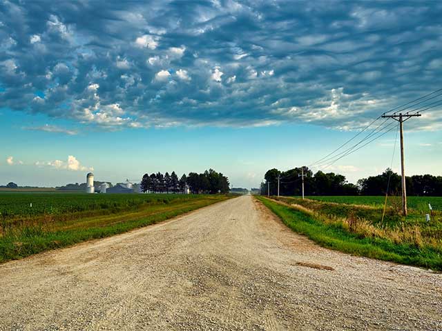 Country road with a silo in the distance